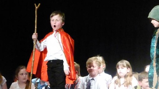 A young boy in a regal outfit performing on stage 