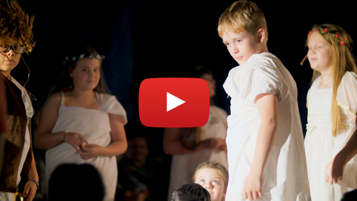Young children in a play looking intense. There is a YouTube icon overlaid on the image