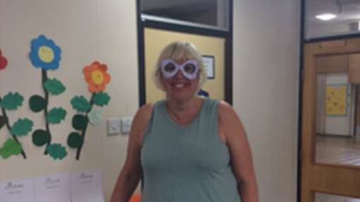 Head teacher at Brinsworth Howarth Primary school stood up in a blue long dress, with a pair of paper goggles on her face.